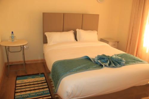 a bedroom with two beds and a small table with a table at Juniper Green Gardens Resort. in Mweiga