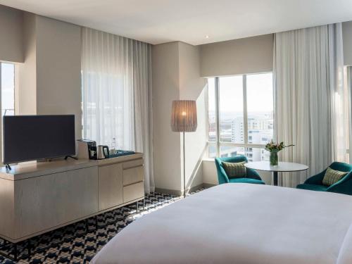 um quarto de hotel com uma cama e uma televisão de ecrã plano em Pullman Cape Town City Centre em Cidade do Cabo