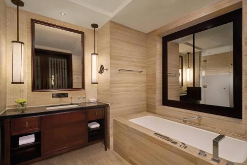 La salle de bains est pourvue d'une baignoire et d'un grand miroir. dans l'établissement Sheraton Shenzhou Peninsula Resort, à Wanning
