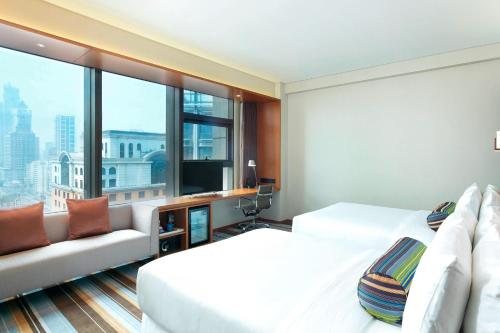 a hotel room with two beds and a couch at Aloft Dalian in Dalian