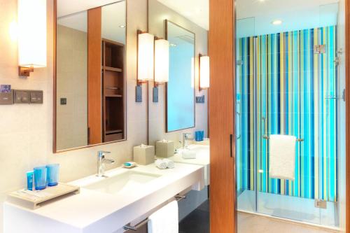 a bathroom with two sinks and two mirrors at Aloft Dalian in Dalian