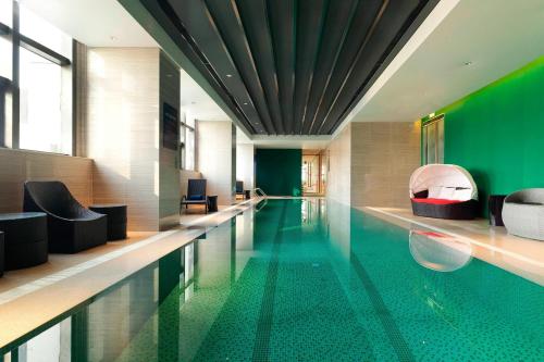 a swimming pool in a building with green walls at Aloft Dalian in Dalian