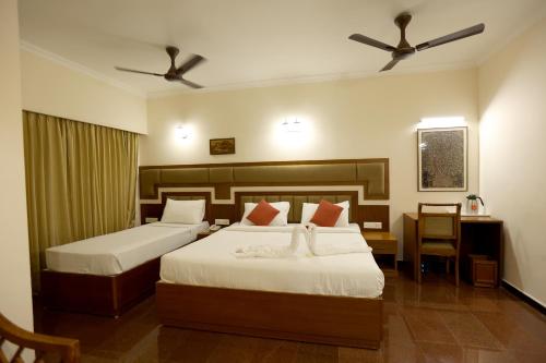 2 camas en una habitación de hotel con 2 ventiladores en Breeze Residency, en Tiruchchirāppalli