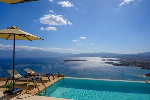 a pool with an umbrella and a view of the ocean at Majestic View Villas in Agios Nikolaos