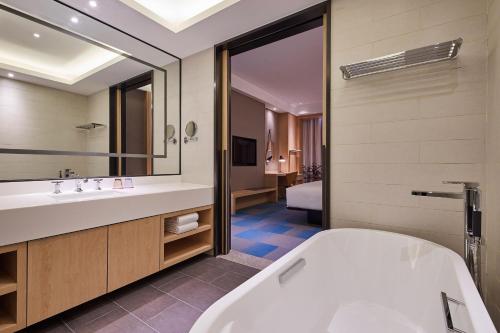 łazienka z wanną i dużym lustrem w obiekcie Aloft Shanghai Zhangjiang Haike w Szanghaju