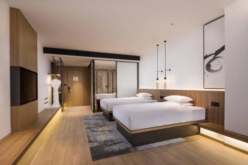 a hotel room with three beds and a television at Fairfield by Marriott Xi'an North Station in Xi'an