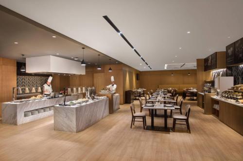 a restaurant with tables and chairs and chefs in the kitchen at Fairfield by Marriott Xi'an North Station in Xi'an