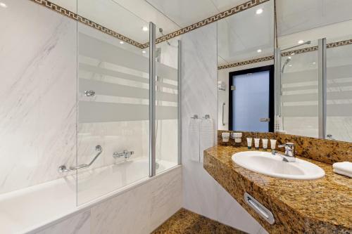 a bathroom with a sink and a shower and a tub at The Westin Leipzig in Leipzig