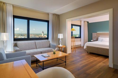a hotel room with a couch and a bed and a room with a view at The Westin Leipzig in Leipzig