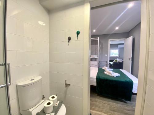 un bagno con servizi igienici e un letto in una camera. di Quarteira Stylish 2 by Homing a Quarteira