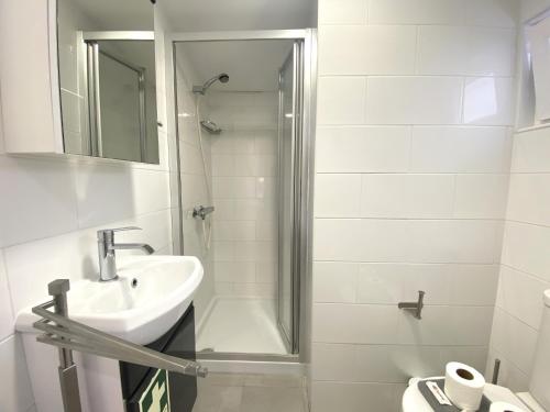 a white bathroom with a sink and a shower at Quarteira Stylish 2 by Homing in Quarteira