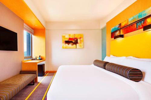 um quarto de hotel com uma cama e uma televisão em Aloft Dynamic Town em Longgang