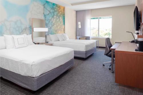 a hotel room with two beds and a desk at Courtyard by Marriott DeLand Historic Downtown in De Land
