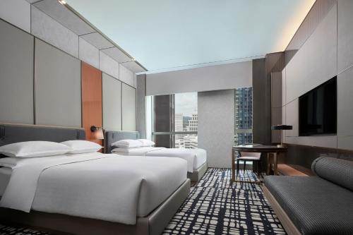 a hotel room with three beds and a television at Sheraton Shenzhen Nanshan in Shenzhen