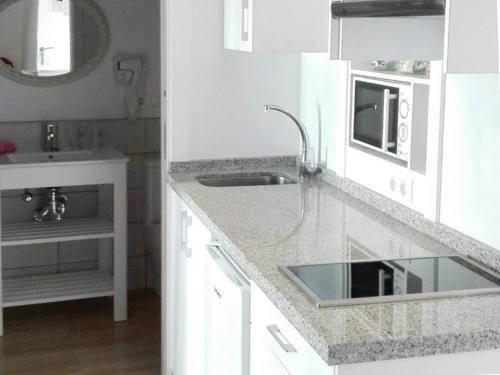 cocina blanca con fregadero y microondas en La Casa de la Costurera en Córdoba
