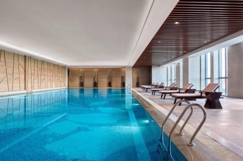 a large swimming pool with chairs in a building at The Westin Hefei Baohe in Hefei
