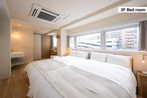 a bedroom with a large white bed with a window at Totonou & GIVE Nakano Sakaue in Tokyo