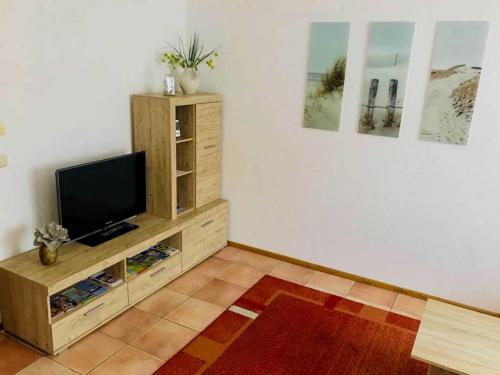 ein Wohnzimmer mit einem TV auf einem hölzernen Entertainment-Center in der Unterkunft Ferienwohnung Herzogstadt in Wolgast