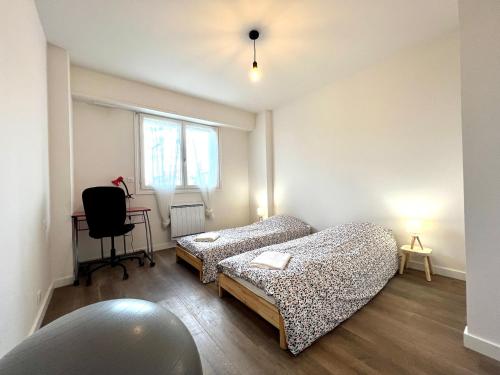 1 dormitorio con 2 camas, escritorio y silla en APPARTEMENT MODERNE ET SPACIEUX AU COEUR DE BIARRITZ 6 pers, en Biarritz