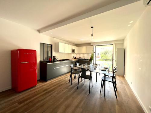Il comprend une cuisine équipée d'un réfrigérateur rouge, d'une table et de chaises. dans l'établissement APPARTEMENT MODERNE ET SPACIEUX AU COEUR DE BIARRITZ 6 pers, à Biarritz