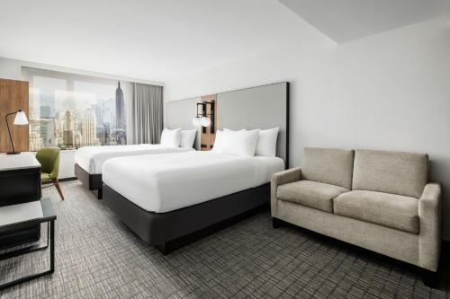 a hotel room with two beds and a couch at Fairfield Inn & Suites by Marriott New York Manhattan/Times Square South in New York