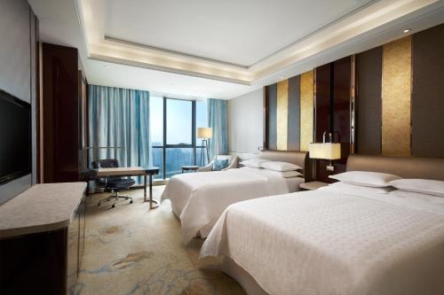 a hotel room with two beds and a television at Sheraton Grand Zhengzhou Hotel in Zhengzhou
