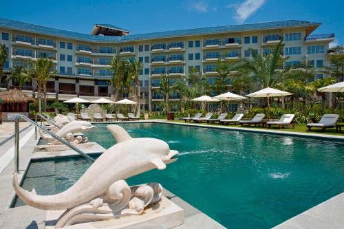 a pool at a resort with statues in the water at Sheraton Huizhou Beach Resort in Huidong