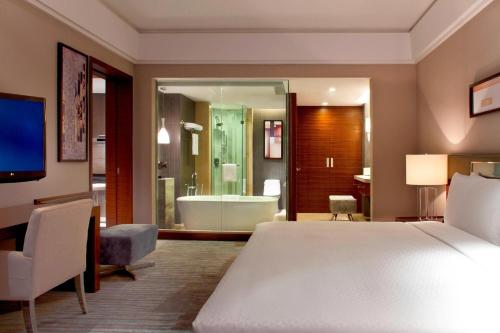 a bedroom with a bed and a bathroom with a tub at Four Points by Sheraton Taicang in Taicang