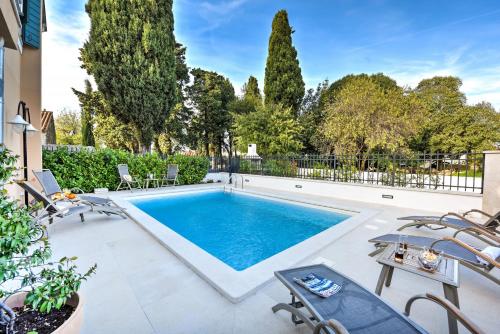 a swimming pool in a yard with chairs and trees at Villa Danica ZadarVillas in Sukošan