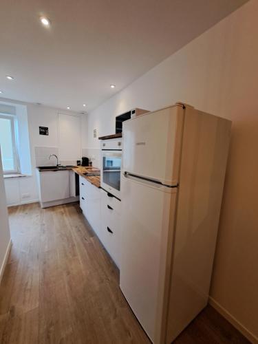 Il comprend une cuisine équipée d'appareils électroménagers blancs et d'un réfrigérateur blanc. dans l'établissement Le Bulotier, à Granville