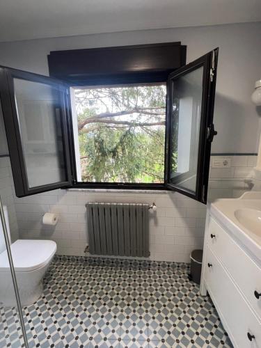 a bathroom with a window and a toilet and a sink at Casa Boni y Florina in Nava