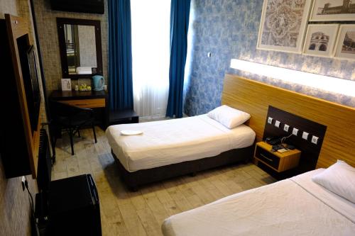a hotel room with two beds and a desk at Esin Hotel in Denizli