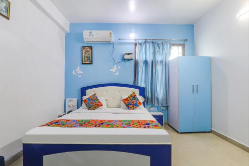 a blue bedroom with a bed and a blue wall at FabExpress JMD Inn in Lucknow