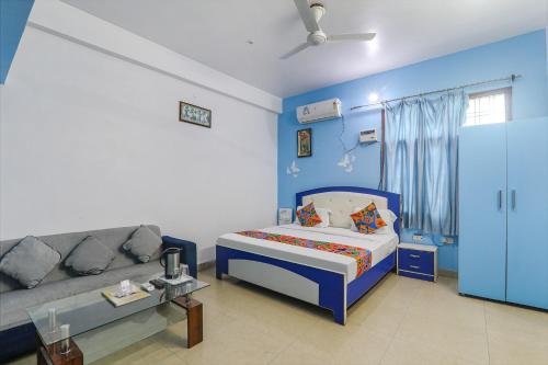 a blue room with a bed and a couch at FabExpress JMD Inn in Lucknow