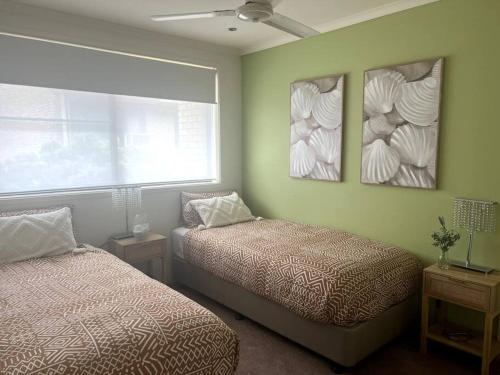 a bedroom with two beds and two pictures on the wall at A touch of lux in the Redlands! in Capalaba