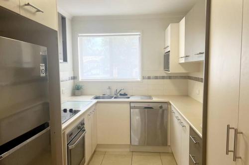 a white kitchen with a sink and a window at A touch of lux in the Redlands! in Capalaba