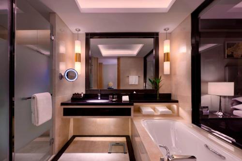 a bathroom with a tub and a sink and a mirror at Sheraton Daqing Hotel in Daqing