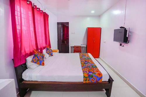 um quarto com uma cama com cortinas vermelhas em FabExpress Lloyds Inn I em Chennai