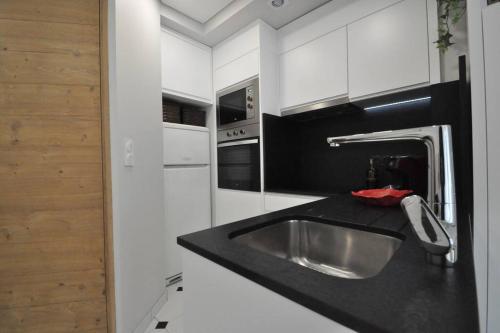 une cuisine avec un évier et un plan de travail noir dans l'établissement Appartement Cocooning calme, à Orléans