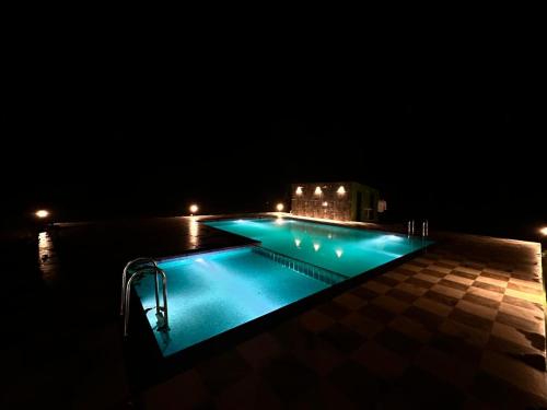 una piscina iluminada por la noche en Pench Tiger Home, 
