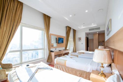 a hotel room with three beds and a window at Alolayan Diamond Hotel in Mecca