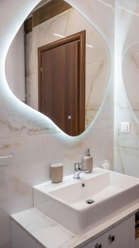 a bathroom with a sink and a mirror at ALBA SUITE APARTMENT in Kalabaka