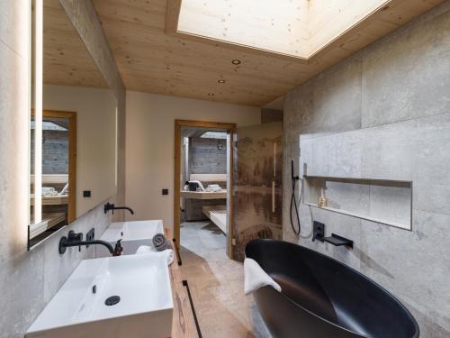 a bathroom with a black tub and a sink at Villa Himmlgassl Private Spa in Zellbergeben