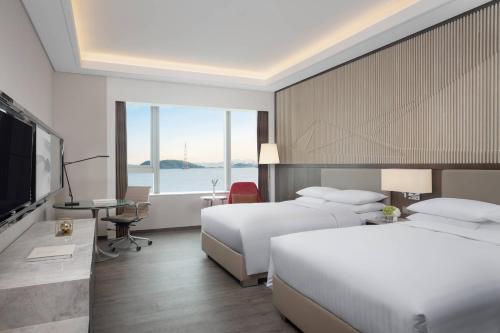 a hotel room with two beds and a flat screen tv at Courtyard by Marriott Xiamen Haicang in Xiamen
