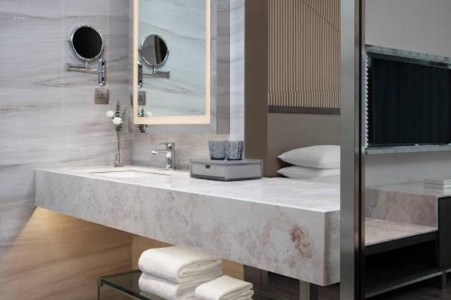 a bathroom with a large marble sink and a television at Courtyard by Marriott Xiamen Haicang in Xiamen