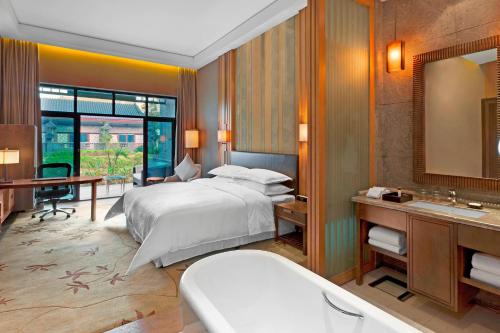 a bedroom with a bed and a sink and a mirror at Sheraton Grand Hangzhou Wetland Park Resort in Hangzhou