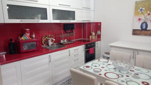 une cuisine avec des placards blancs et un mur rouge dans l'établissement Апартамент-Надин, à Krumovgrad