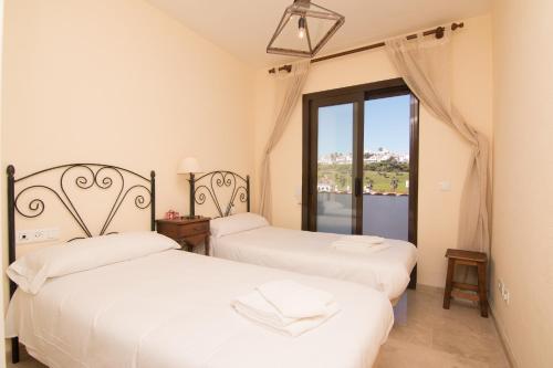 two beds in a room with a window at 2233-Lovely 2 bedrooms on the beach, pool and port in Manilva