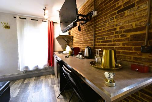 a kitchen with a counter and a brick wall at Appartement jacuzzi privatif : Urban Love in Verneuil d’Avre et d’Iton