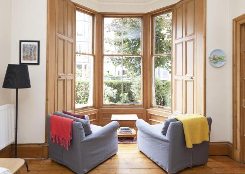 ein Wohnzimmer mit 2 Stühlen und einem großen Fenster in der Unterkunft ALTIDO 3-bed Meadows flat near Castle in Edinburgh
